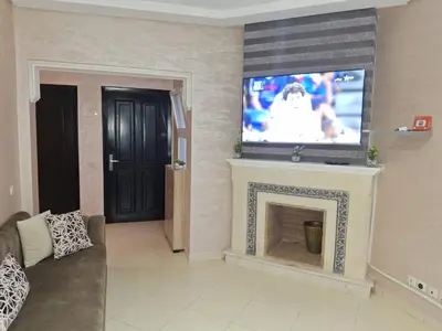 a living room with a fireplace with a tv above it at Garden Beach 2 sidi rahal in Sidi Rahal