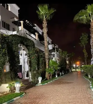 a cobblestone street with palm trees and a building at Garden Beach 2 sidi rahal in Sidi Rahal
