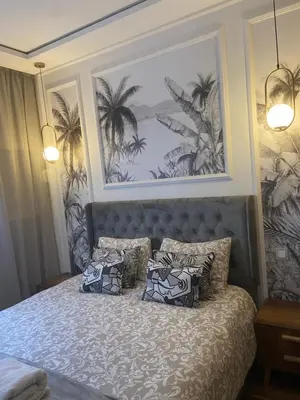 a bedroom with a bed with palm trees on the wall at Charmant appartement 2 chambres à Casablanca, à 10 min de la plage in Casablanca