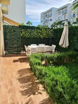 a patio with a table and an umbrella at Appartement résidence kettani jardin privatif accès direct piscine et aire de jeu in Bouznika