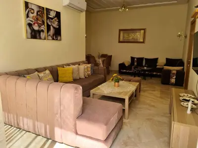 a living room with a couch and a table at Appartement résidence kettani jardin privatif accès direct piscine et aire de jeu in Bouznika
