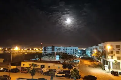a city at night with the moon in the sky at Blue Themed Vacation Condo in Temara