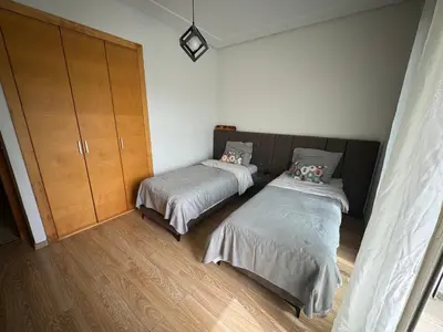 a bedroom with two beds and a cabinet at Golf City Prestigia Bouskoura in Bouskoura