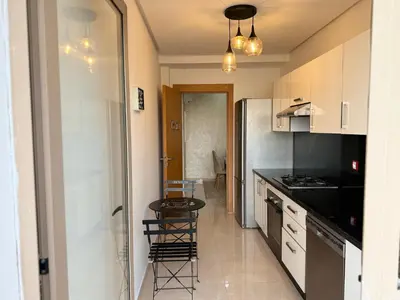 a kitchen with white cabinets and a table and chairs at Douce escale vue sur piscine - Costa Beach bouznika in Bouznika