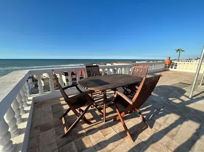 a wooden table and two chairs sitting on a patio near the beach at Villa Taroub avec piscine et vue sur mer in Temara