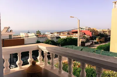 a person sitting on a balcony looking at the ocean at Villa Taroub avec piscine et vue sur mer in Temara