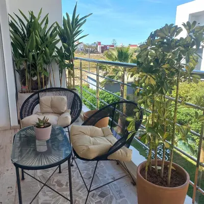 a balcony with two chairs and a table and a plant at Puerto Marina Dar Bouazza in Dar Bouazza