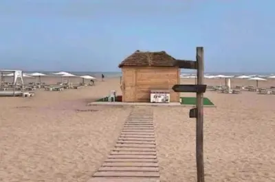 a small building on a beach with chairs and umbrellas at Beach condo at Casabay plage Sidi Rahal in Casablanca
