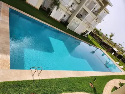 an overhead view of a blue swimming pool in front of a building at Beach condo at Casabay plage Sidi Rahal in Casablanca
