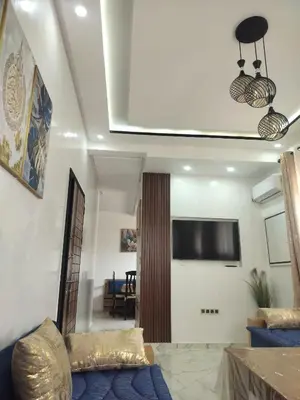 a living room with a blue couch and a tv at Dahomey city in Bouznika