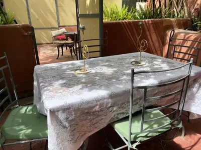 a table with a white table cloth and chairs at Lovely flat in nice garden in Rabat
