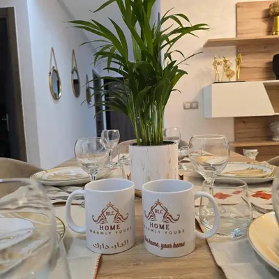 a table with two mugs and a potted plant on it at Appartement charmant au parc de Mohammedia, à seulement 2 pas de la plage in Mohammedia