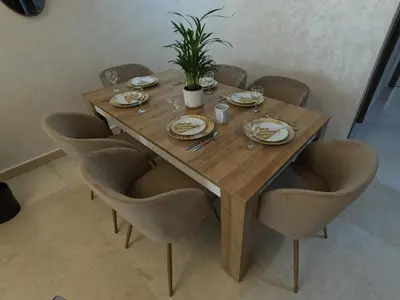 a wooden table with chairs and plates and a plant on it at Appartement charmant au parc de Mohammedia, à seulement 2 pas de la plage in Mohammedia