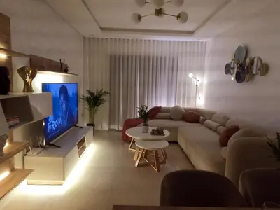 a living room with a couch and a tv at Appartement charmant au parc de Mohammedia, à seulement 2 pas de la plage in Mohammedia