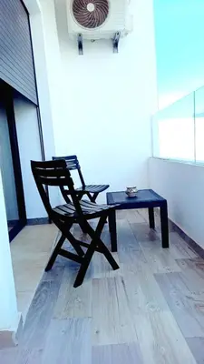a chair and a table in a room at Appartement spacieux au cœur du Parc Proche plage Entre Casa et Rabat in Mohammedia