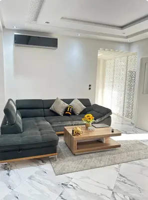 a living room with a black couch and a coffee table at Chambre à Agdal Rabat dans un appartement partagé -two single beds- in Rabat