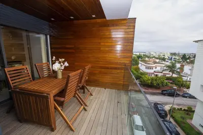 a patio with a wooden table and chairs on a balcony at Appartement raffiné dans un quartier de luxe in Rabat