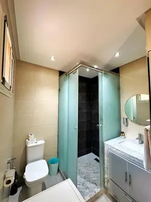 a bathroom with a toilet and a glass shower at Classic & Comfy Apartment, Steps to Sea & Tarmway in Rabat