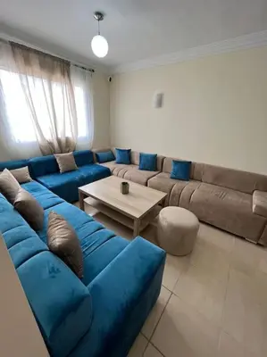 a living room with a blue couch and a table at Appartement Sidi Rahal in Sidi Rahal
