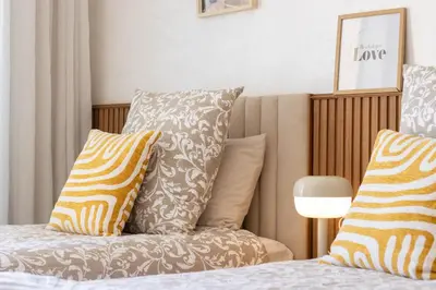 a bed with pillows on top of it next to a lamp at Fun and Sun - Appartement de luxe - Dahomey Beach - Bouznika in Bouznika