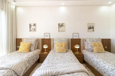 two beds in a room with white walls at Fun and Sun - Appartement de luxe - Dahomey Beach - Bouznika in Bouznika