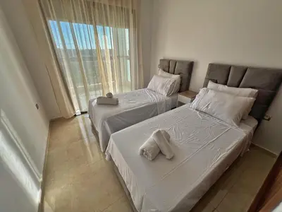 two beds in a hotel room with towels on them at Séjour Chic - Appartement Moderne avec Piscine in Bouznika