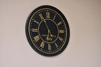 a black clock with roman numerals on a wall at Bens White House in AÃ¯n el Ksob