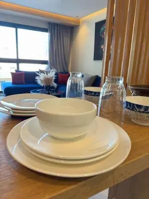 a table with a white bowl and plates on it at Classy presidential apartment in Casablanca
