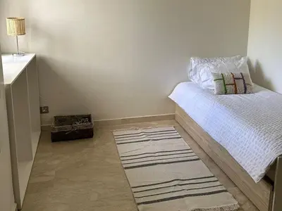 a small bedroom with a bed and a rug at Appartement haut standing près de la Plage in Skhirat