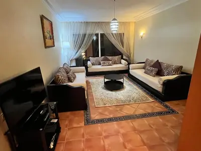 a living room with two couches and a tv at Appartement de H standing in Bouznika