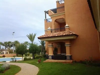 a large building with a balcony next to a pool at Appartement de H standing in Bouznika
