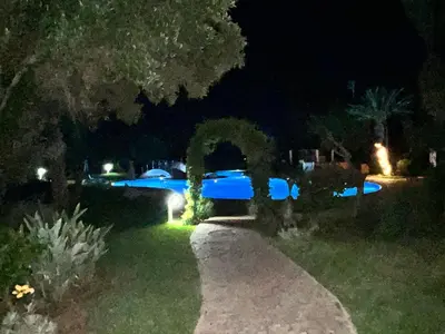a garden at night with a swimming pool at Appartement de H standing in Bouznika