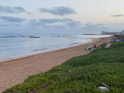 a sandy beach with chairs and the ocean at Maison d'hôte sur la Plage de Bouznika in Bouznika