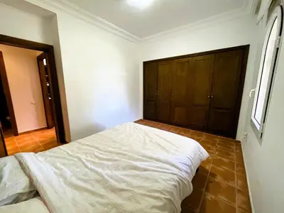 a bedroom with a white bed in a room at Appartement de plain-pied, piscine et mer in Bouznika