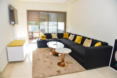 a living room with a black couch and yellow pillows at Le Joyau du Parc in Mohammedia