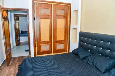 a bedroom with a bed and a wooden door at MOHAMMEDIA Rico Flores in Mohammedia