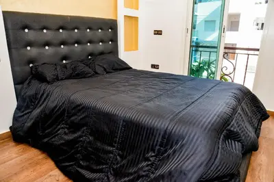 a black bed in a bedroom with a black headboard at MOHAMMEDIA Rico Flores in Mohammedia