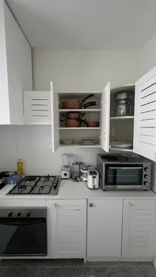 a white kitchen with a microwave and a stove at Appartement spacieux - BD Anfa in Casablanca