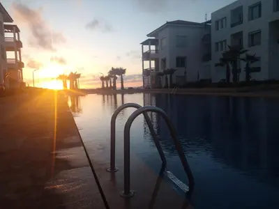 a pool of water with the sun setting in the background at Cité Marine in Mansouria