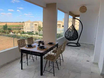 a dining room with a table and chairs and a large window at Appartement de luxe avec vue sur mer in Bouznika