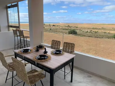 a dining room table with chairs and a view of the desert at Appartement de luxe avec vue sur mer in Bouznika