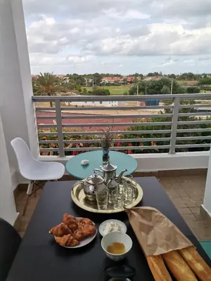 a table with a tray of food on a balcony at Grand appartement vue golf a 2 min de la plage Bouznika in Bouznika