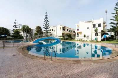 a large swimming pool with a slide in front of some buildings at Maison avec Piscine Proche Plage in El Harhoura
