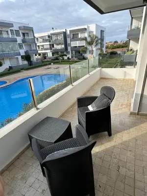 a balcony with chairs and a swimming pool on a building at Cozy New Apartment in Tamaris in Dar Bouazza