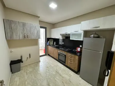 a kitchen with a refrigerator and a stove at Cozy New Apartment in Tamaris in Dar Bouazza
