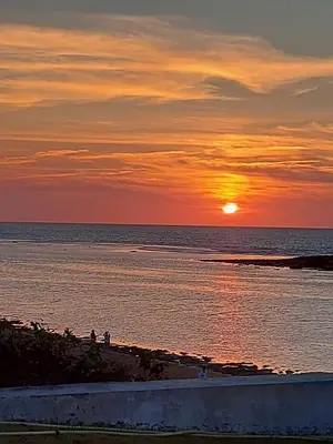 a sunset over the ocean with people on the beach at Villa pied dans l'eau skhirat in Skhirat