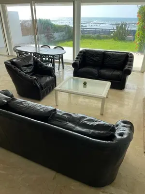 a living room with black leather furniture and a table at Villa pied dans l'eau skhirat in Skhirat