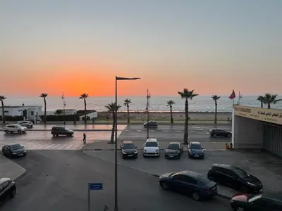 a parking lot with cars parked in front of the ocean at Garsoniere Borj in Rabat