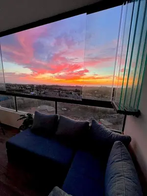 a couch in front of a large window with a sunset at Appartement a zenata ain-harrouda casablanca in Mohammedia