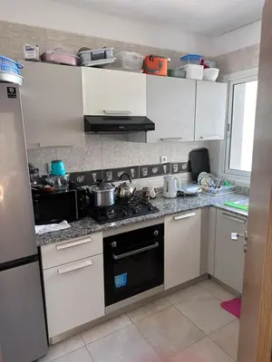a kitchen with white cabinets and a stove top oven at Appartement 2 Chambres in Sidi Rahal
